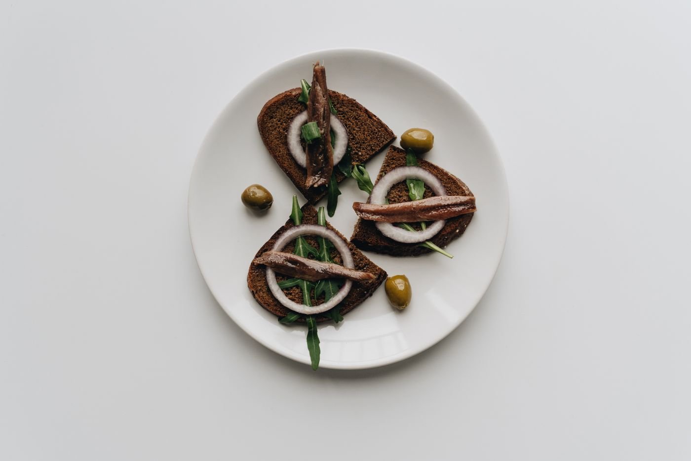 Anchovy Rye Toasts with Onion Rings and Arugula